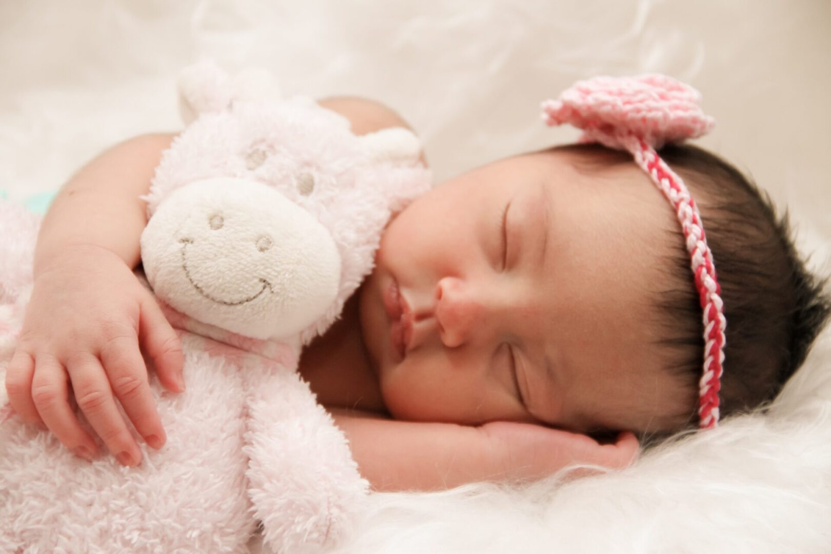 A baby sleeping with her head on a stuffed animal.